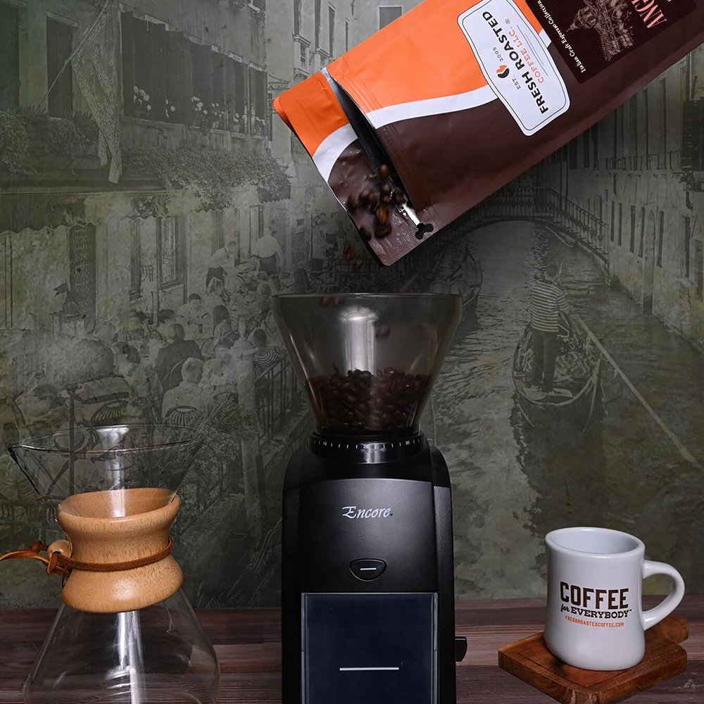 Fresh Roasted Coffee Anguissola beans being poured into a coffee grinder, ready for a fresh espresso brew.